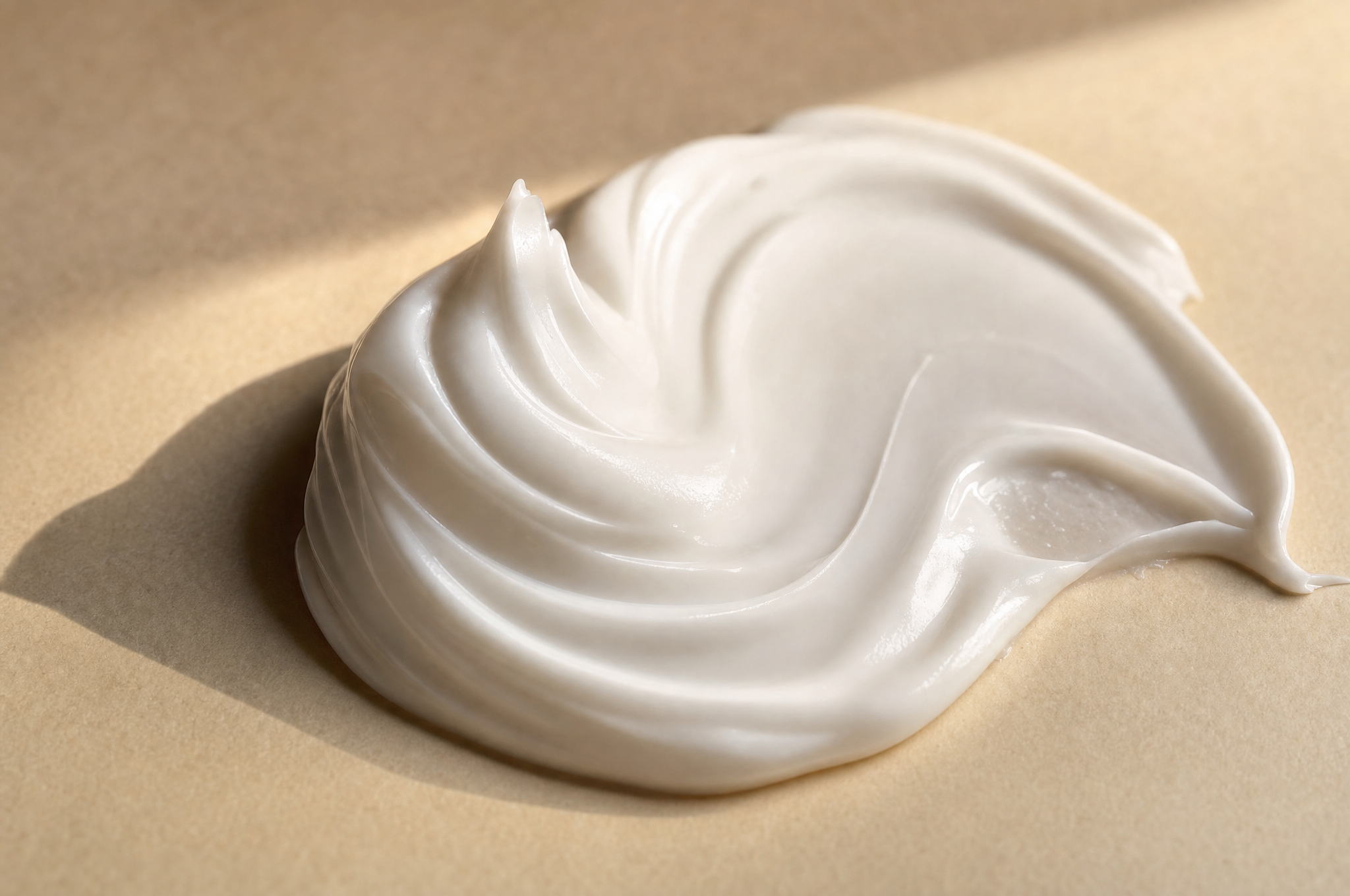 A swirl of white non-greasy Handvela cream on a warm cream surface